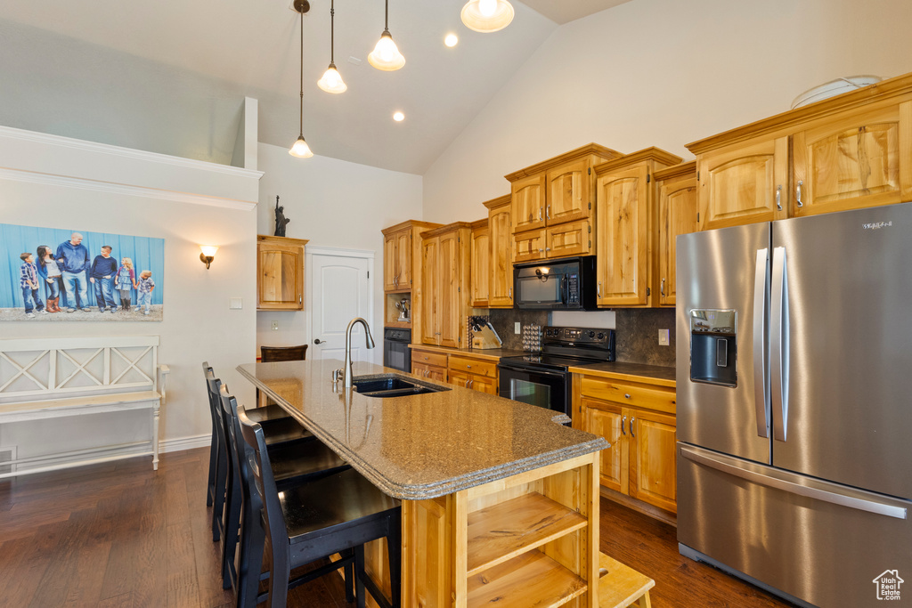 Kitchen featuring a sink, a kitchen bar, high vaulted ceiling, black appliances, and a center island with sink