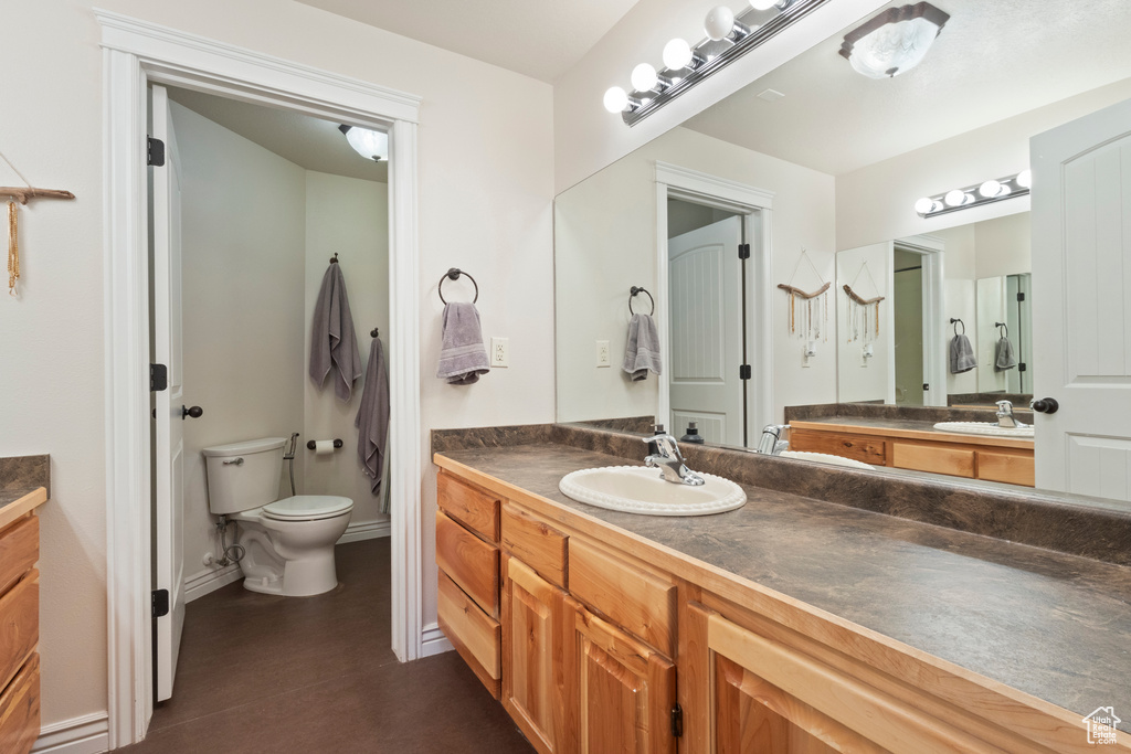 Full bathroom with toilet, baseboards, and vanity