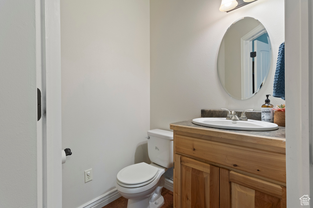 Bathroom featuring toilet, baseboards, and vanity