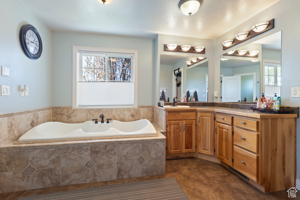 Full bathroom featuring tile patterned floors, a garden tub, double vanity, and a sink