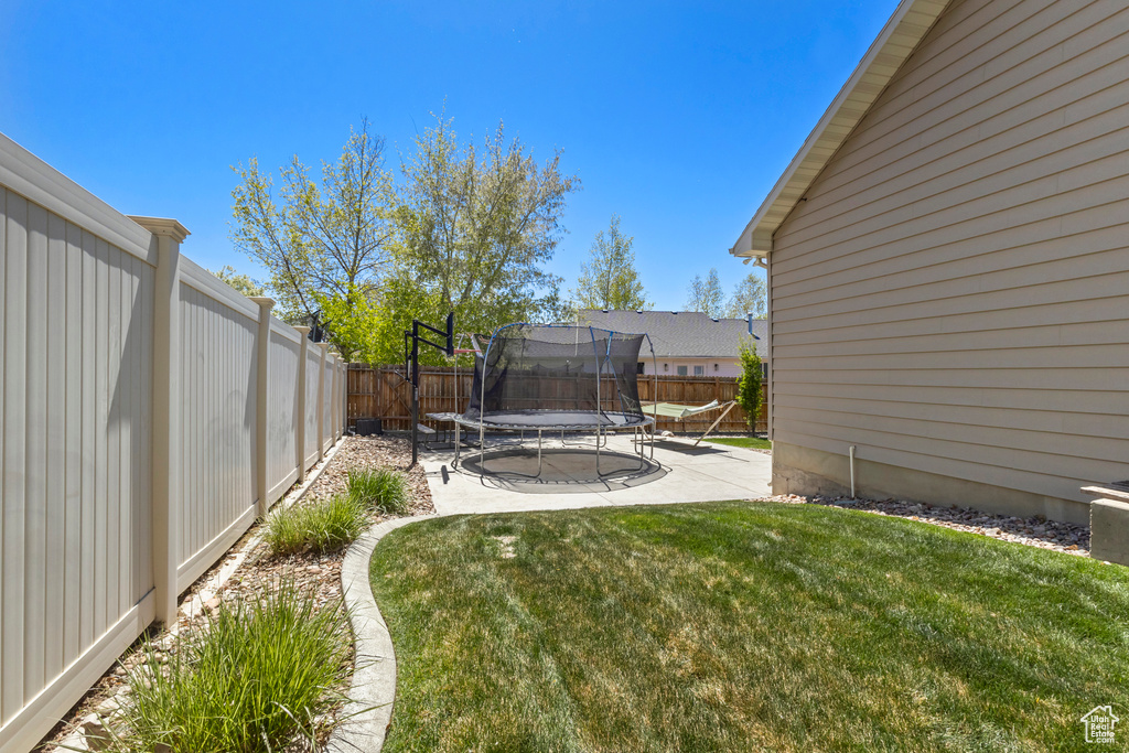 View of yard featuring a fenced backyard, a patio area, and a trampoline