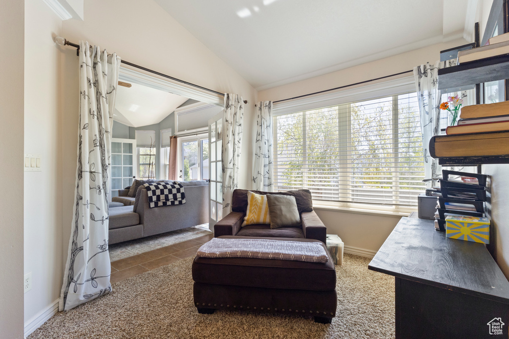 Living area with tile patterned floors, vaulted ceiling, and baseboards