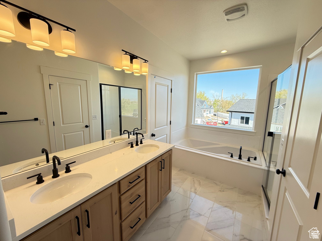 Bathroom featuring double vanity, a bath, and a sink
