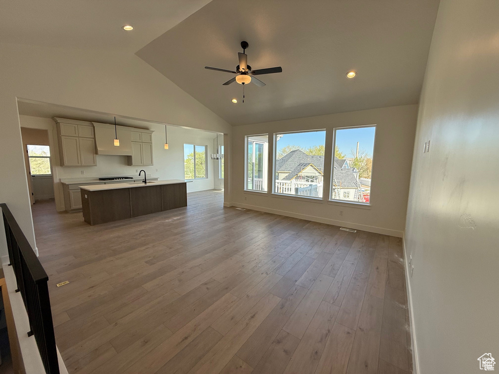 Living area featuring a healthy amount of sunlight, light wood-style flooring, ceiling fan, and high vaulted ceiling