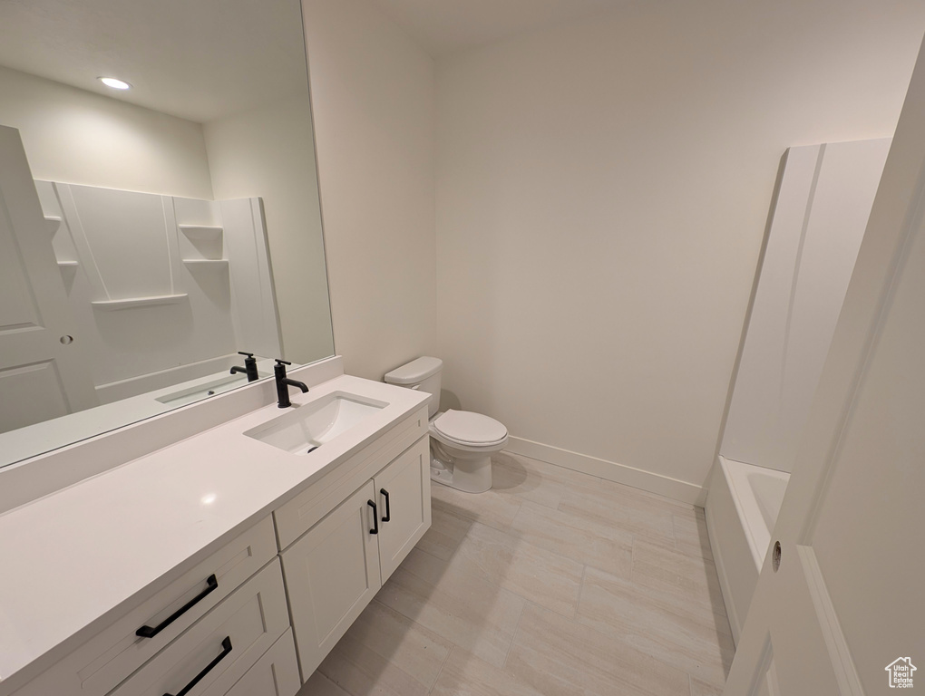 Bathroom with vanity, toilet, baseboards, and recessed lighting