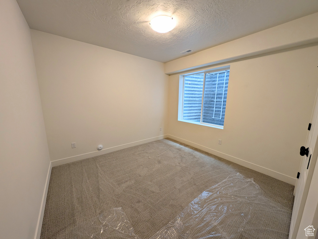 Unfurnished room featuring a textured ceiling, carpet flooring, and baseboards