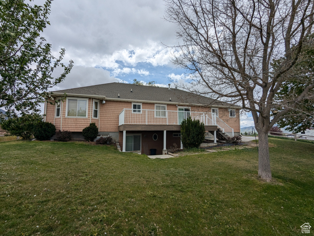 Back of property with a yard, a deck, and stairs