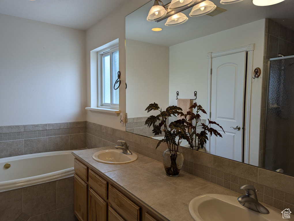 Bathroom featuring a shower stall, a bath, double vanity, and a sink