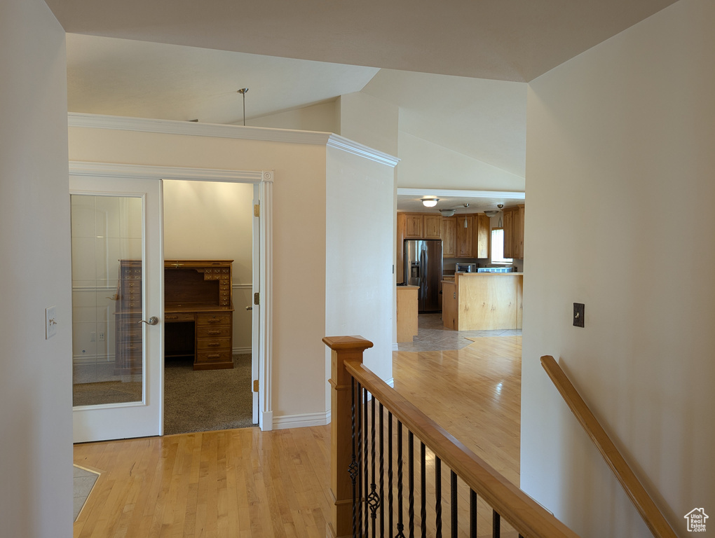 Hall featuring light wood finished floors, lofted ceiling, baseboards, and an upstairs landing