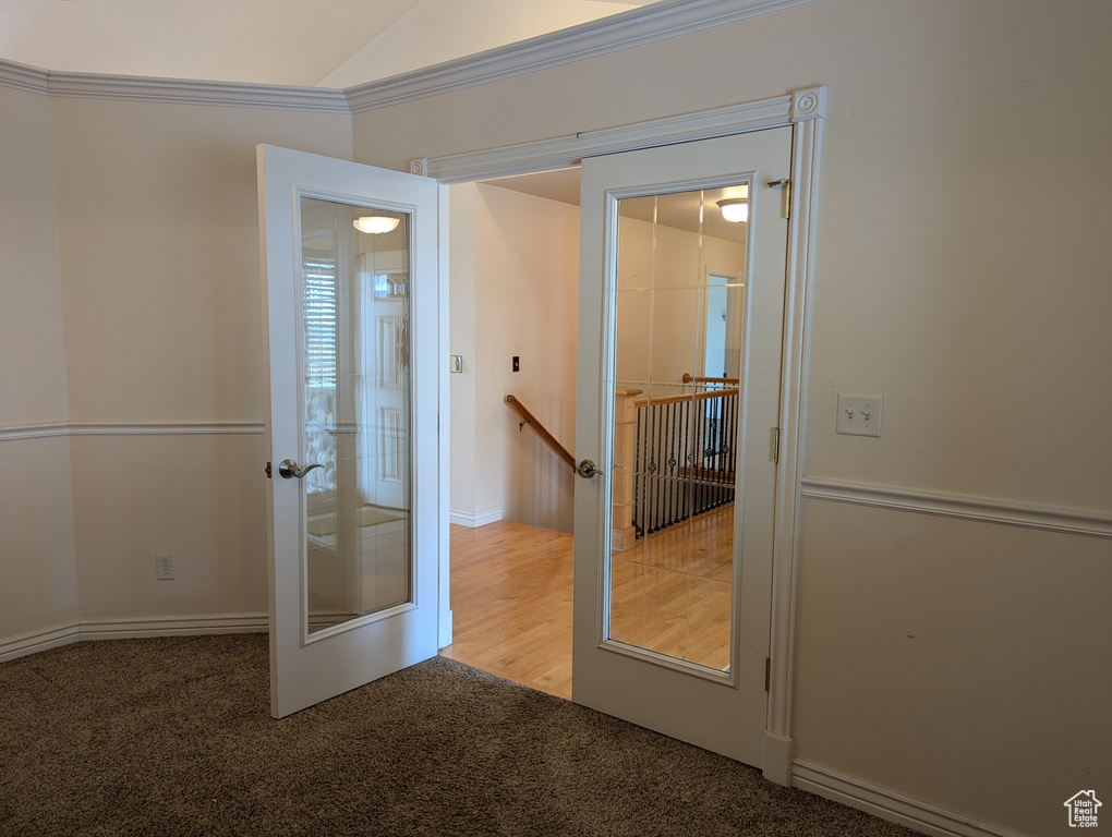 Entryway featuring lofted ceiling, ornamental molding, french doors, and carpet floors