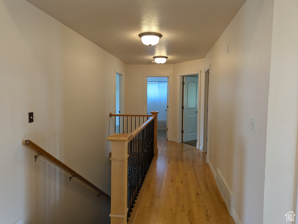Hallway featuring baseboards, visible vents, an upstairs landing, and light wood-style flooring