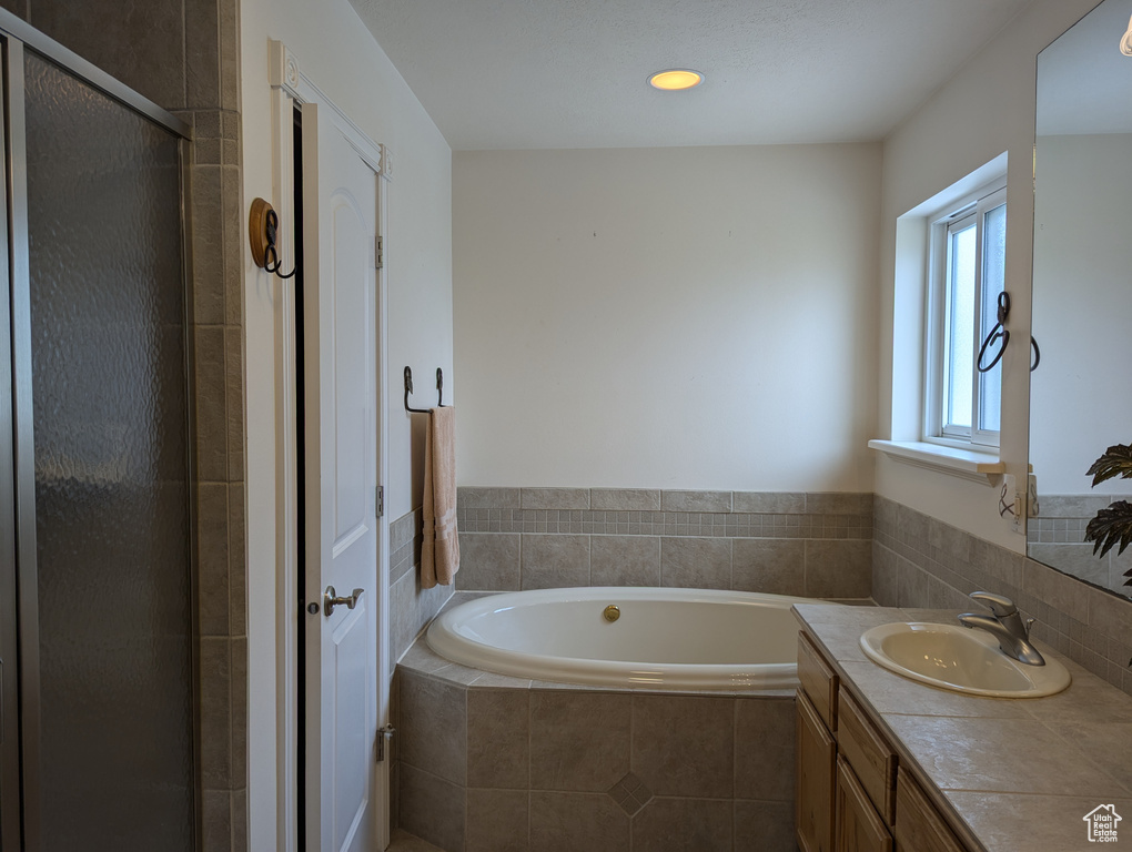 Full bathroom featuring a stall shower, vanity, recessed lighting, and a bath