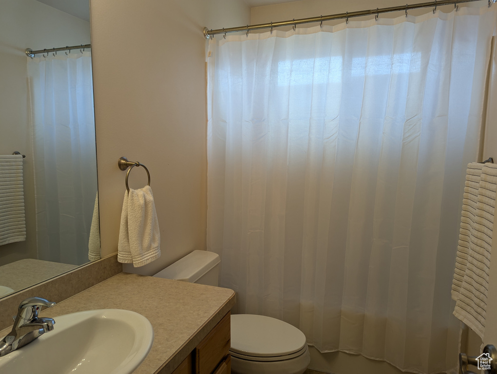 Full bathroom featuring toilet, shower / bath combo, and vanity