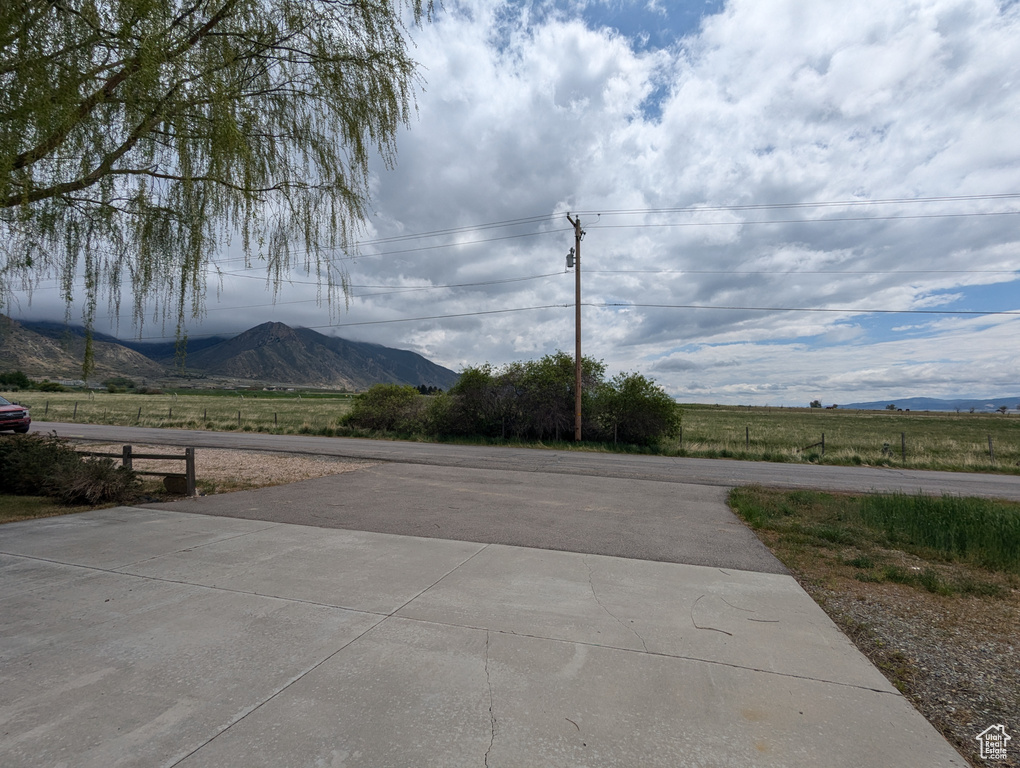 View of street with concrete driveway, a mountain view, and a rural view