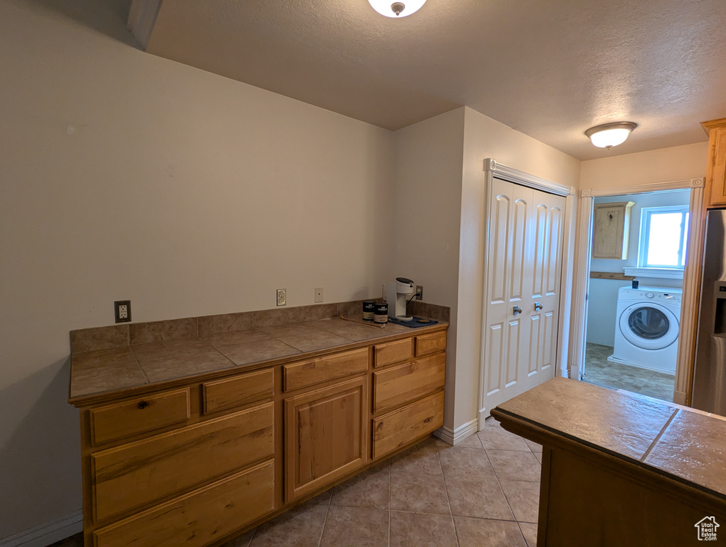 Laundry room with washer / clothes dryer, laundry area, a textured ceiling, light tile patterned flooring, and baseboards