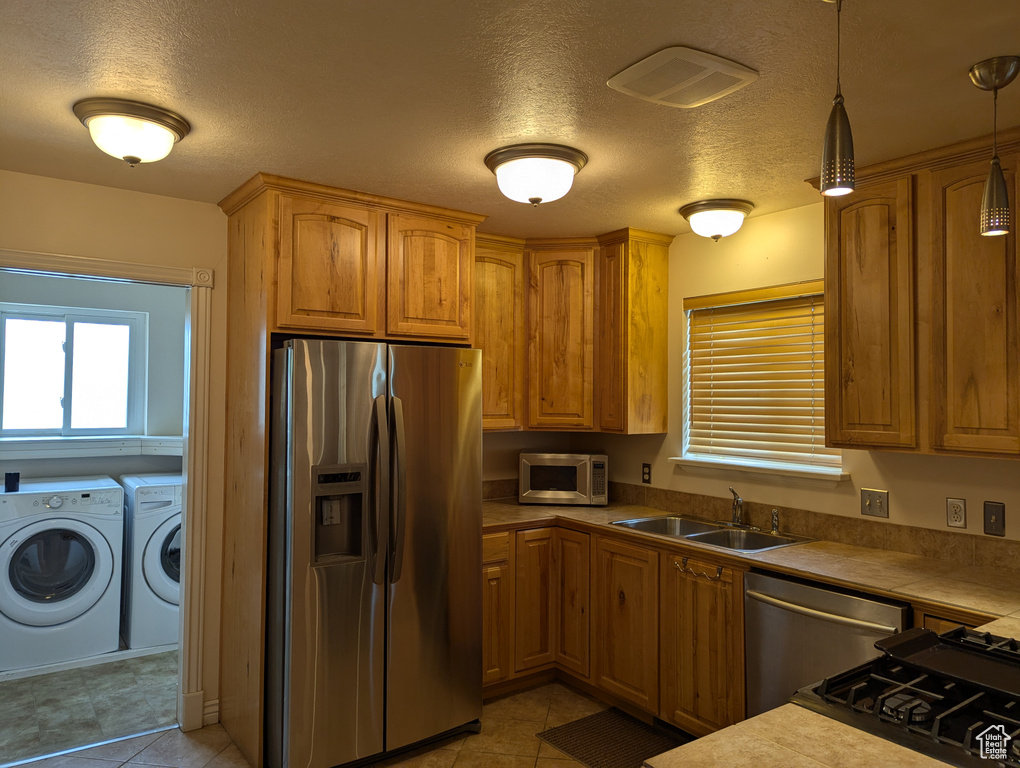 Kitchen featuring washer and dryer, a sink, stainless steel appliances, a textured ceiling, and visible vents