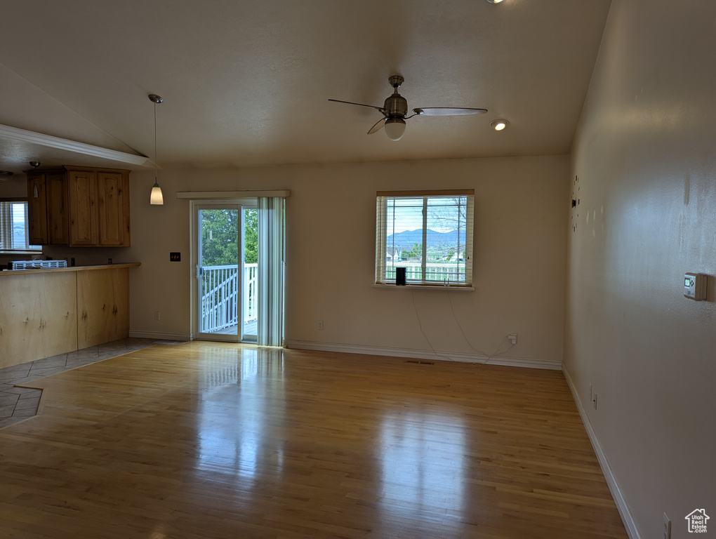 Unfurnished living room featuring vaulted ceiling, ceiling fan, baseboards, and wood finished floors
