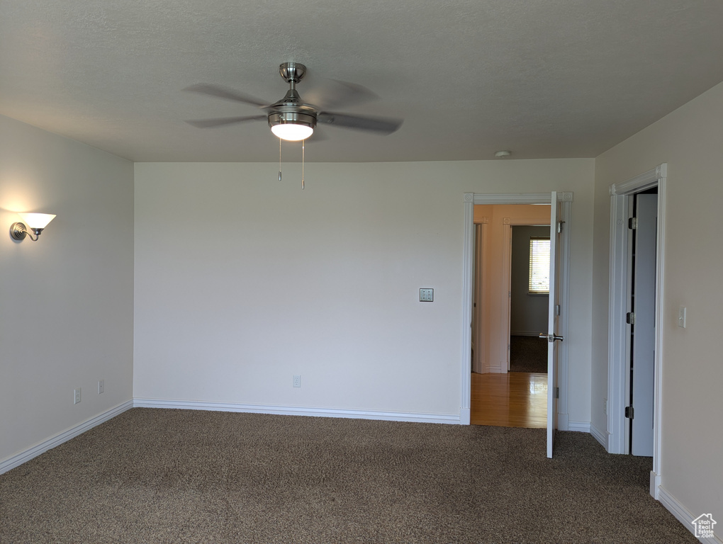 Carpeted empty room featuring baseboards and a ceiling fan