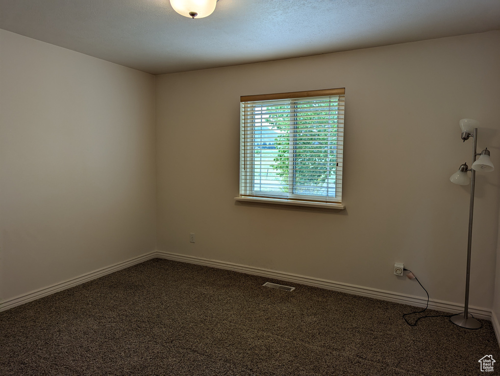 Carpeted spare room featuring baseboards and visible vents