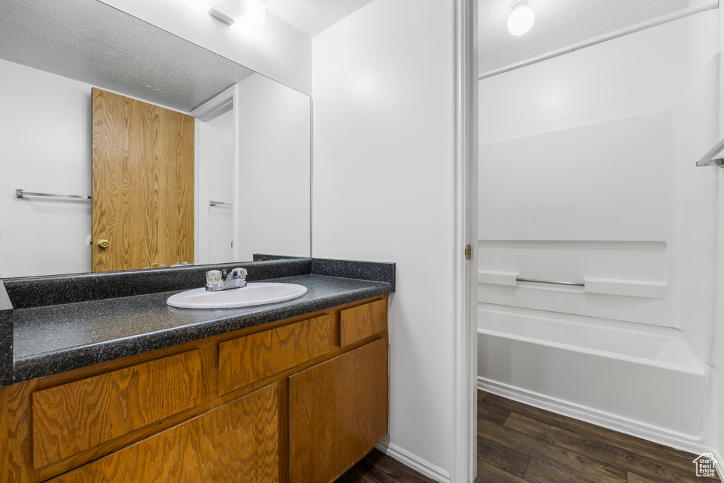 Full bathroom with vanity, a bathing tub, and wood finished floors