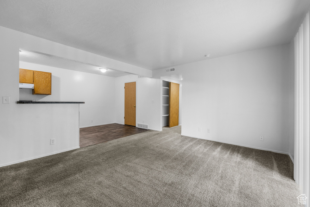 Unfurnished living room featuring dark colored carpet, baseboards, and visible vents