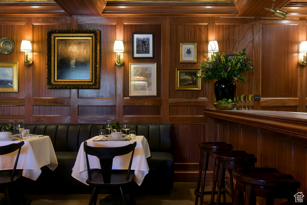 Dining space with coffered ceiling, wooden walls, and ornamental molding