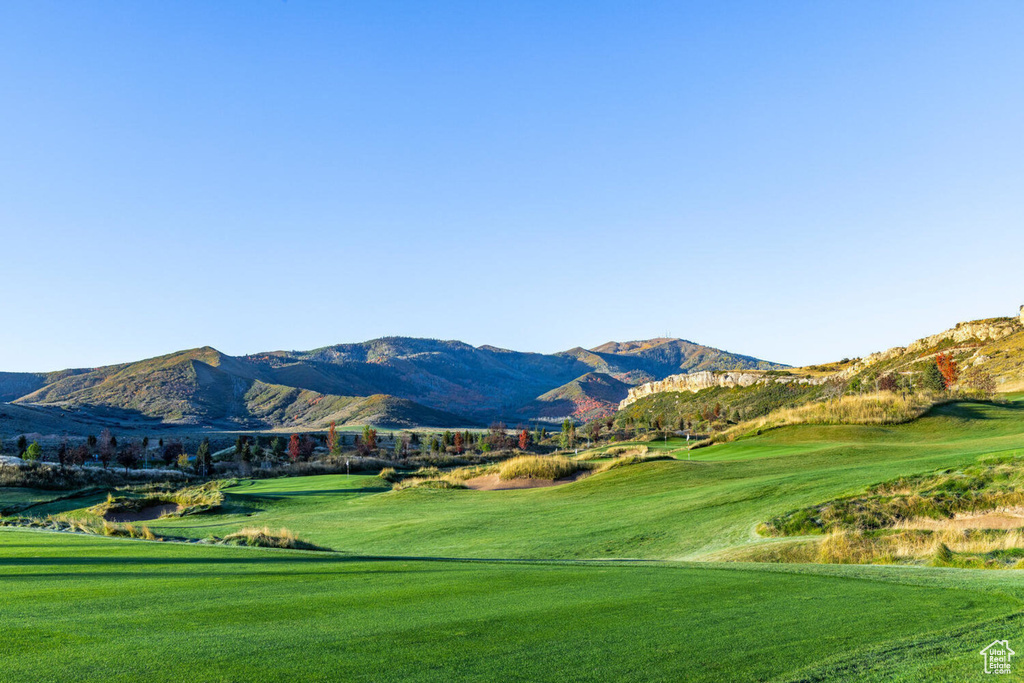 View of home's community featuring view of golf course, a mountain view, and a lawn