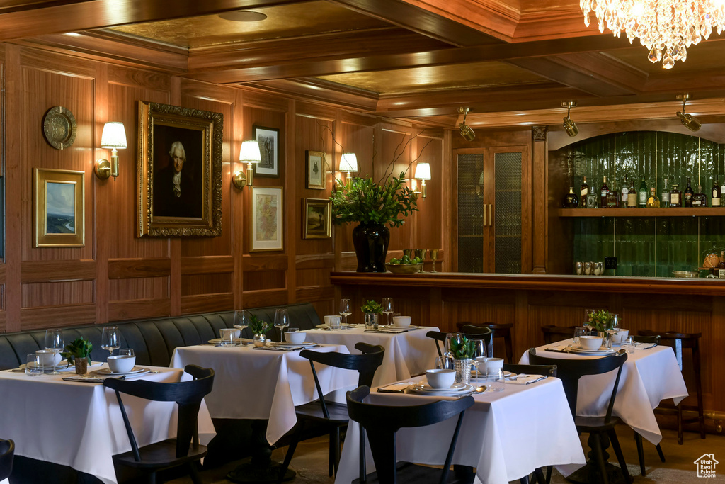 Interior space featuring coffered ceiling, crown molding, wood walls, and a chandelier