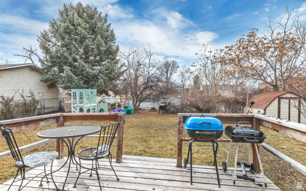 Wooden deck featuring a lawn, area for grilling, and fence
