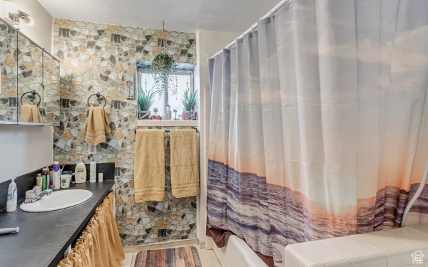 Full bath featuring a textured ceiling and vanity