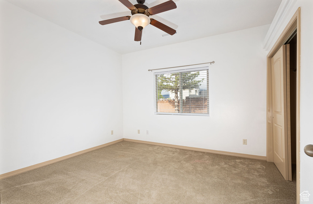 Unfurnished bedroom with ceiling fan, light carpet, and baseboards