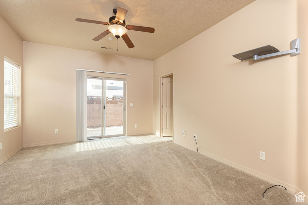 Carpeted empty room with baseboards, visible vents, ceiling fan, and a textured ceiling