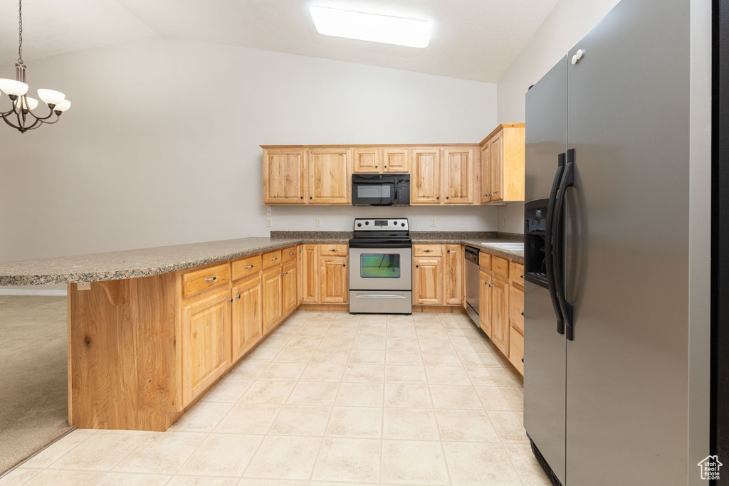 Kitchen with vaulted ceiling, a peninsula, an inviting chandelier, and appliances with stainless steel finishes