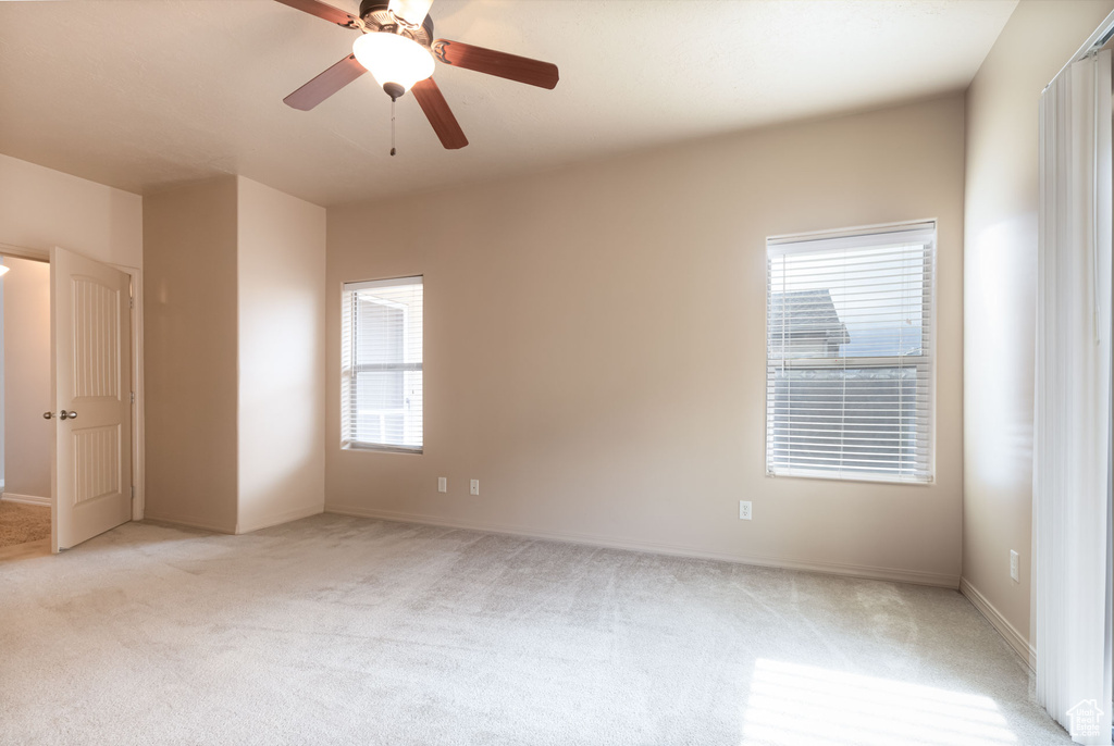 Spare room with light colored carpet, baseboards, and a ceiling fan