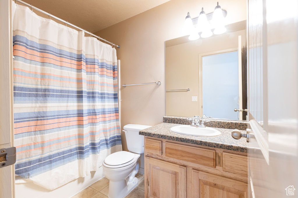 Full bath featuring shower / bath combo with shower curtain, toilet, tile patterned flooring, and vanity