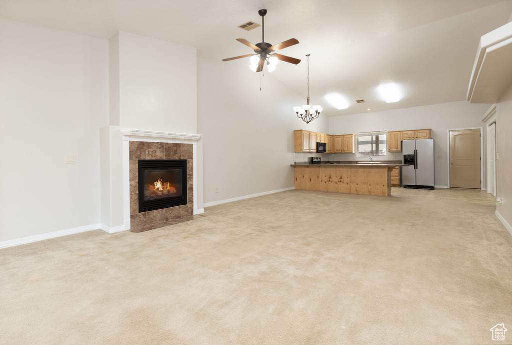 Unfurnished living room with baseboards, a tile fireplace, visible vents, and ceiling fan with notable chandelier