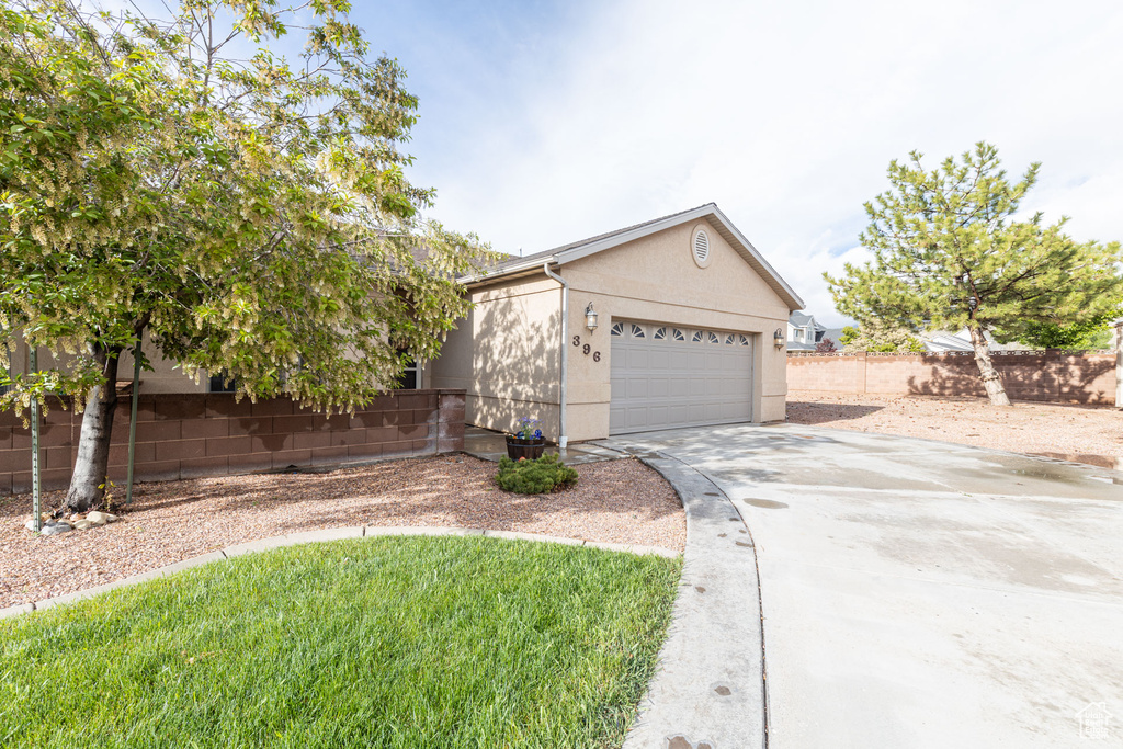 Single story home featuring concrete driveway, stucco siding, an attached garage, and fence