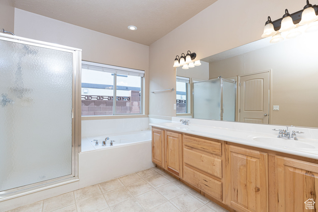 Bathroom featuring double vanity, a garden tub, a shower stall, and a sink