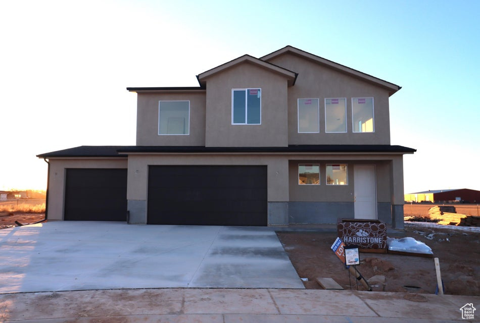 View of front of home featuring a garage, stucco siding, and driveway