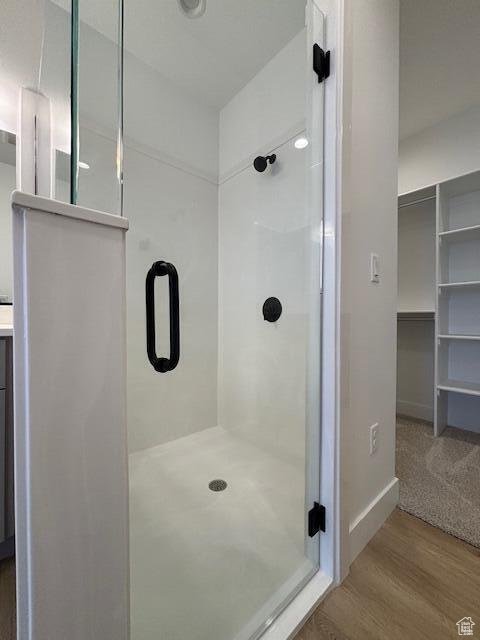 Full bathroom featuring a stall shower, baseboards, and wood finished floors