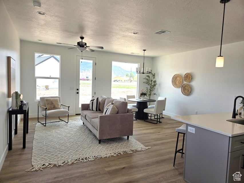 Living area with a textured ceiling, visible vents, baseboards, and wood finished floors