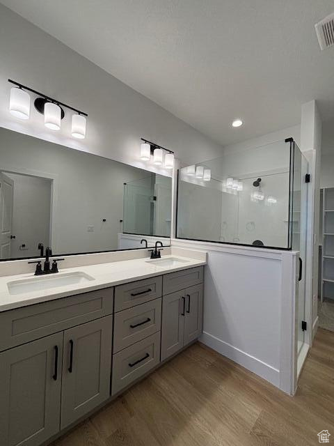 Bathroom with walk in shower, visible vents, wood finished floors, and a sink