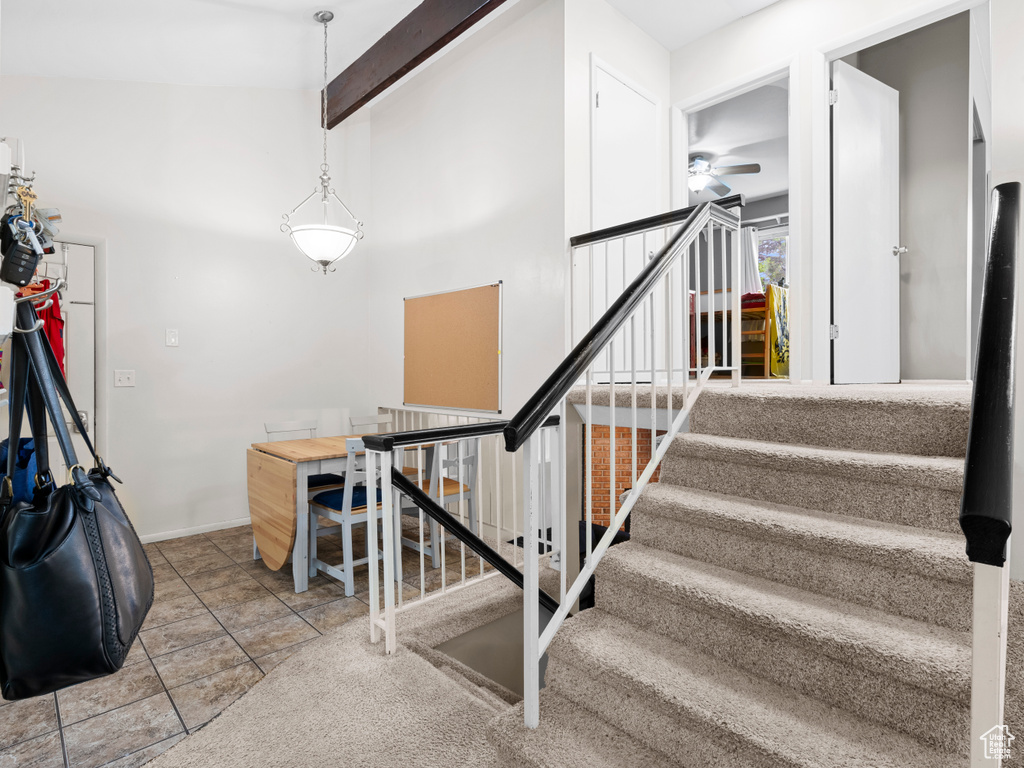 Stairway with beamed ceiling, tile patterned floors, and ceiling fan