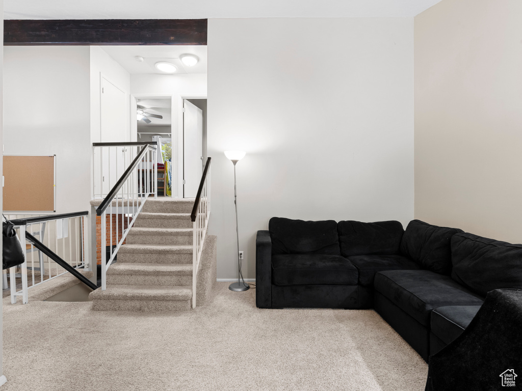 Living area featuring stairs, carpet, and a ceiling fan