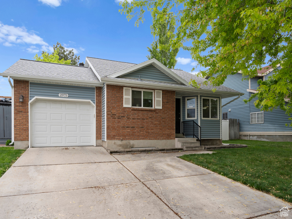 Single story home with a garage, concrete driveway, a shingled roof, a front yard, and brick siding