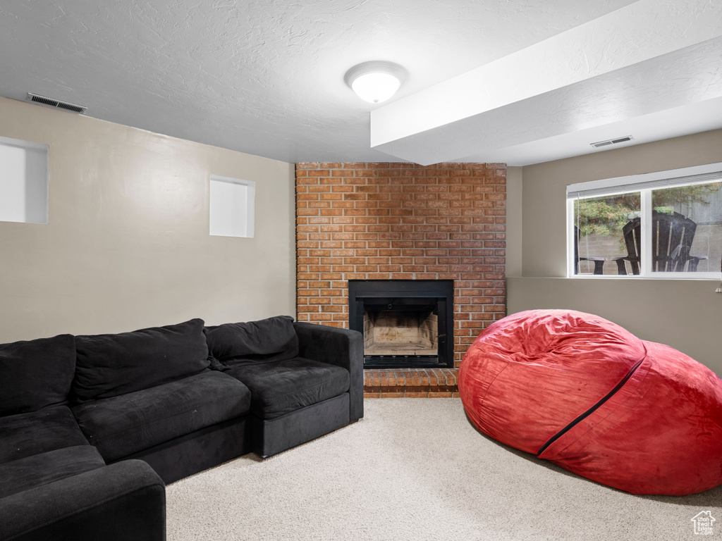 Carpeted living area featuring a brick fireplace and visible vents