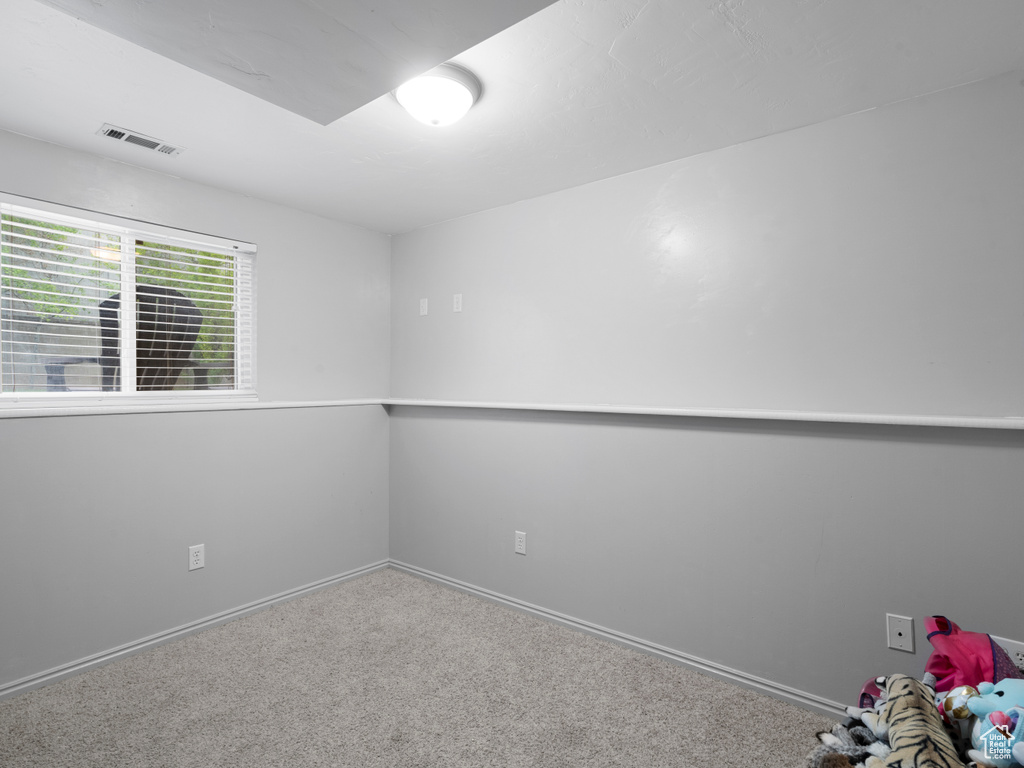 Empty room featuring carpet, visible vents, and baseboards