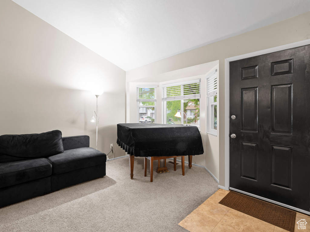 Carpeted foyer entrance featuring vaulted ceiling and baseboards