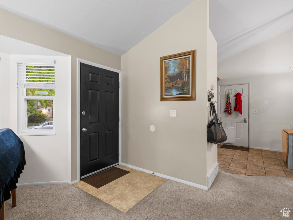 Carpeted foyer featuring lofted ceiling, baseboards, and tile patterned flooring