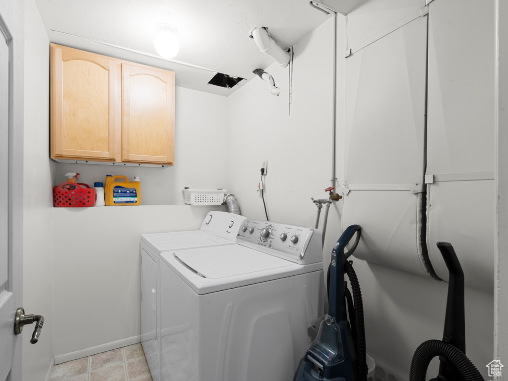 Clothes washing area featuring baseboards, independent washer and dryer, and cabinet space